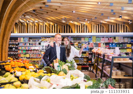 Portrait of a happy young couple with products in a cart in the supermarket 111333931