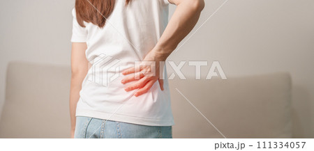 woman having back body ache during sitting on Couch at home. adult female with muscle pain due to Piriformis Syndrome, Low Back Pain and Spinal Compression. Office syndrome and medical concept 111334057