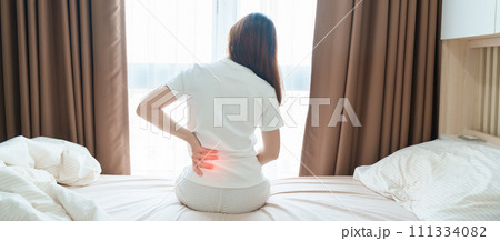 woman having back body ache during sitting on bed at home. adult female with muscle pain after Waking up due to Piriformis Syndrome, Low Back Pain and Spinal Compression. Health medical concept woman having back body ache during sitting on bed at home. adult female with muscle pain after Waking up due to Piriformis Syndrome, Low Back Pain and Spinal Compression. Health medical concept 111334082
