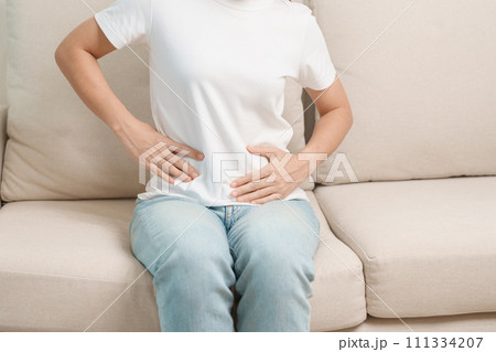 woman having abdomen ache due to Stomach pain, digestion with constipation or Diarrhea from food poisoning, female problem and Endometriosis, Hysterectomy and Menstrual on the sofa at home 111334207