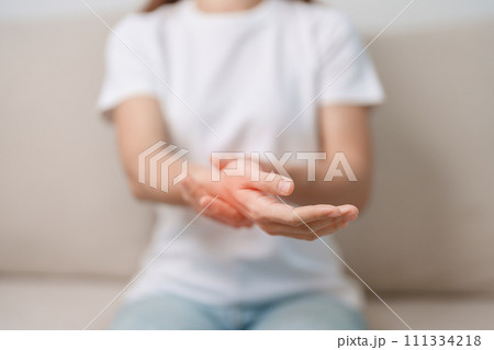 Woman having wrist pain during sitting on sofa at home, muscle ache due to De Quervain s tenosynovitis, ergonomic, Carpal Tunnel Syndrome or Office syndrome concept 111334218