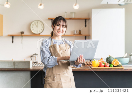 家のキッチンでノートパソコンを使ってレシピや栄養素を検索するアジア人女性 家のキッチンでノートパソコンを使ってレシピや栄養素を検索するアジア人女性 111335421