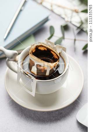 Drip coffee bag with ground coffee in cup. Drip coffee bag with ground coffee in cup. 111335765