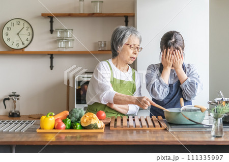 料理を見て文句を言う高齢者女性と泣く若い女性(嫁いびり) 料理を見て文句を言う高齢者女性と泣く若い女性(嫁いびり) 111335997