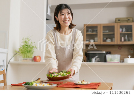 料理を配膳する女性・笑顔の主婦 料理を配膳する女性・笑顔の主婦 111336265
