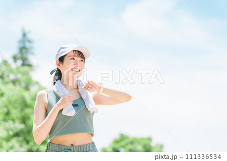 公園でスマートウォッチを見ながら運動・トレーニング・ウォーキングする女性(時間・タイム・ヘルスケア) 111336534