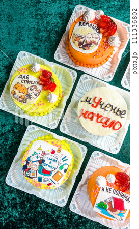 Colorful Cupcakes with Intricate Frosting Designs in Plastic Containers on Green Background Colorful Cupcakes with Intricate Frosting Designs in Plastic Containers on Green Background 111336802