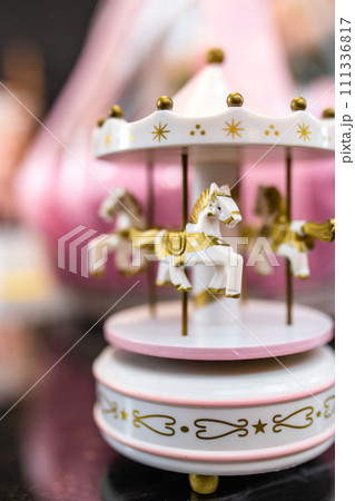 White and pink music carousel with gold horses on dark background 111336817