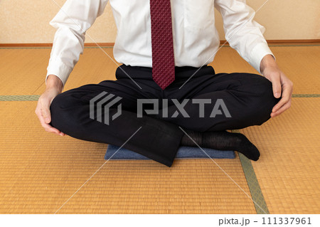 座布団の上にあぐらをかく白いワイシャツ姿の男性 111337961