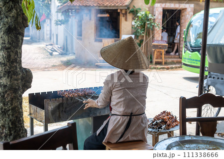 ベトナムハノイ 国家文化財に指定されたドンラム村レストランの店先で焼き鳥を焼く女性 ベトナムハノイ 国家文化財に指定されたドンラム村レストランの店先で焼き鳥を焼く女性 111338666