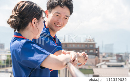病院の屋上で話す医者・医師・看護師・医療従事者・ドクター・作業療法士・理学療法士の男女 111339026