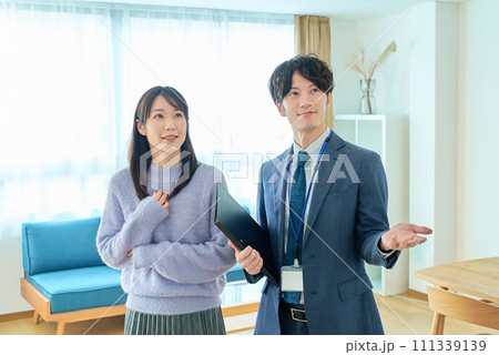 女性に部屋を説明するスーツ姿の男性 女性に部屋を説明するスーツ姿の男性 111339139