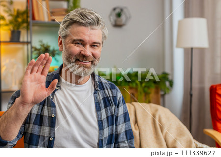 Happy mature man smiling friendly at camera, waving hands gesturing hello, hi, greeting, welcome 111339627