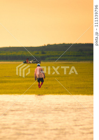 A farmer is walking in the fields. An old man is walking in the swamp. A farmer is walking in the fields. An old man is walking in the swamp. 111339796