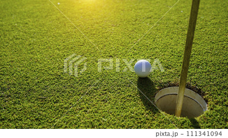 Top view of a golf ball on green course at hole. Top view of a golf ball on green course at hole. 111341094