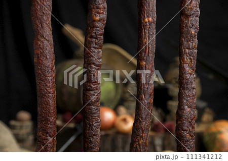 Smoked, aged sausages hanging in the kitchen Smoked, aged sausages hanging in the kitchen 111341212