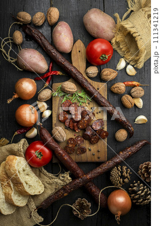 Smoked, aged sausages with fresh vegetables and food ingrediets on the wooden table. Flat lay, Top view 111341219