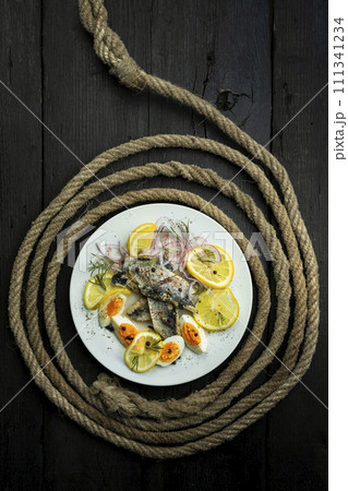 Herring fish fillets with eggs, herbs, onion and lemon on a white plate. Top view, flat lay photo 111341234