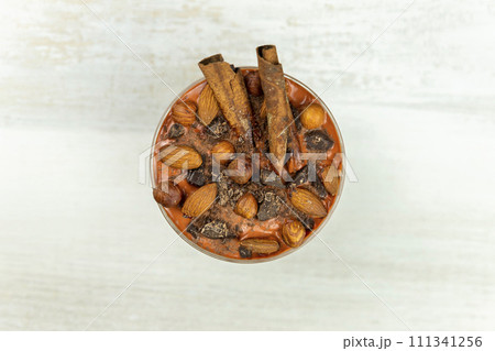 Smoothie or pudding with chocolate, hazelnuts and almonds served in a bowl for breakfast. Flat lay image Smoothie or pudding with chocolate, hazelnuts and almonds served in a bowl for breakfast. Flat lay image 111341256