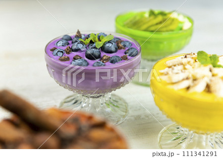Smoothie or pudding with blueberries and chocolate served in a bowl for breakfast with several other smoothies in background Smoothie or pudding with blueberries and chocolate served in a bowl for breakfast with several other smoothies in background 111341291