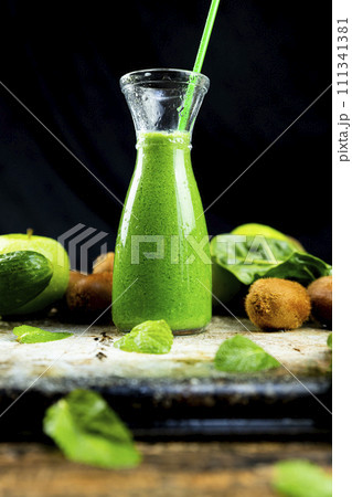 Healthy green smoothies with spinach, apple, kiwi, broccoli and mint in glass jar with fruits and vegetables on the wooden table. Detox and healthy concept 111341381