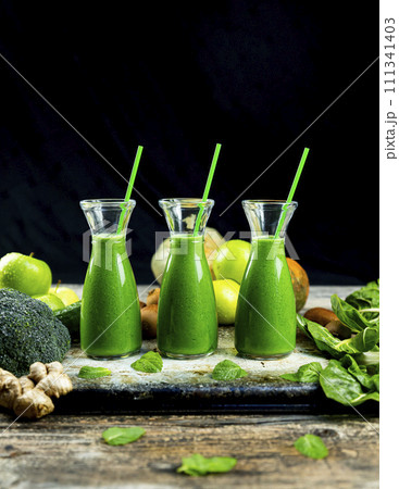 Healthy green smoothies with spinach, apple, kiwi, broccoli and mint in glass jar with fruits and vegetables on the wooden table. Detox and healthy concept 111341403