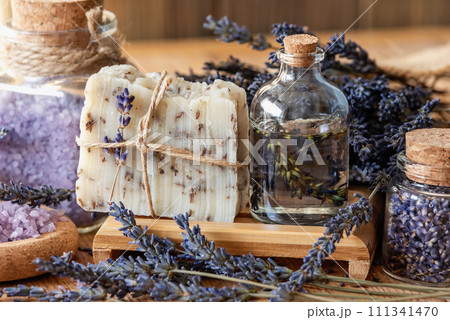 Wellness treatments with lavender flowers on wooden table. Spa still-life. Essential oils, sea salt and handmade soap. Natural herb cosmetic with lavender flowers Wellness treatments with lavender flowers on wooden table. Spa still-life. Essential oils, sea salt and handmade soap. Natural herb cosmetic with lavender flowers 111341470
