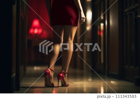 A woman's red heels elegantly stride on a city street, with the night's ambiance enhancing the mood 111343583
