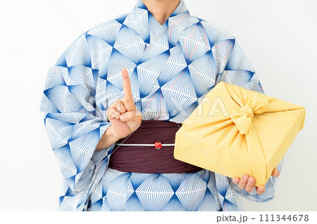 浴衣姿でお中元の風呂敷包みを持って人差し指を立てるミドル女性 111344678