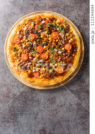 Homemade Spicy Mexican Taco PIzza with ground beef, tomatoes, corn, black beans, cheddar cheese, red onion on the wooden board. Vertical top view 111344894