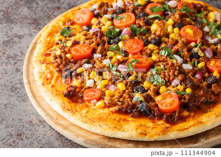 Spicy Mexican Taco pizza with ground beef, tomatoes, corn, black beans, cheddar cheese, red onion on the wooden board. Horizontal Spicy Mexican Taco pizza with ground beef, tomatoes, corn, black beans, cheddar cheese, red onion on the wooden board. Horizontal 111344904