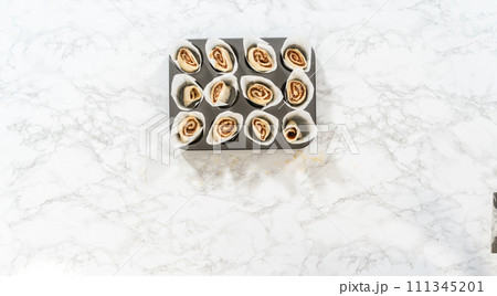 Flat lay. Filling cupcake liners with small cinnamon rolls to bake no-yeast cinnamon roll cupcakes. Flat lay. Filling cupcake liners with small cinnamon rolls to bake no-yeast cinnamon roll cupcakes. 111345201