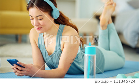Smartphone, yoga and headphones of woman typing on chat app for fitness communication, social media update or blog writing wellness. Pilates girl with exercise gear and technology in home living room Smartphone, yoga and headphones of woman typing on chat app for fitness communication, social media update or blog writing wellness. Pilates girl with exercise gear and technology in home living room 111345724