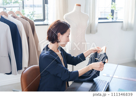 服をチェックしてパソコンにデータ入力する女性 服をチェックしてパソコンにデータ入力する女性 111346839
