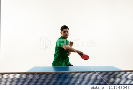 Dynamic portrait of athletic Asian man, professional ping-pong player training techniques in motion against white studio background. Dynamic portrait of athletic Asian man, professional ping-pong player training techniques in motion against white studio background. 111348048