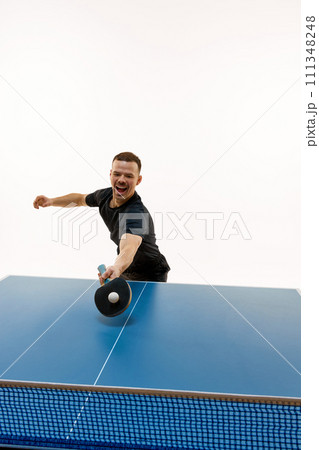 Young man, table tennis competitor in mid-swing during competitive match against white background. Professional sport. 111348248