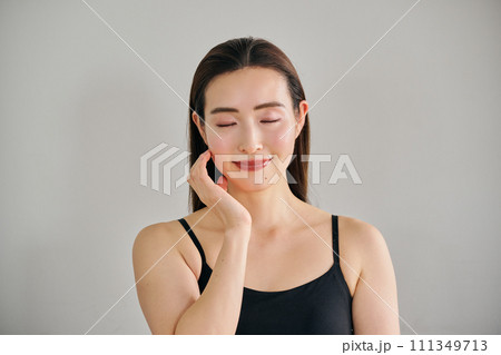 顔をマッサージして肌のお手入れをする30代女性 111349713