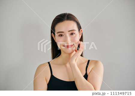 顔をマッサージして肌のお手入れをする30代女性 111349715