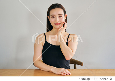 顔をマッサージして肌のお手入れをする30代女性 111349718