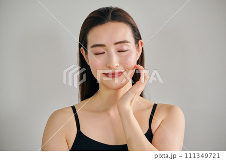 顔をマッサージして肌のお手入れをする30代女性 111349721