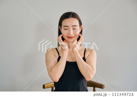 顔をマッサージして肌のお手入れをする30代女性 111349728