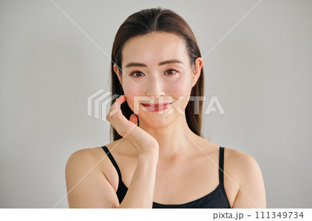 顔をマッサージして肌のお手入れをする30代女性 顔をマッサージして肌のお手入れをする30代女性 111349734