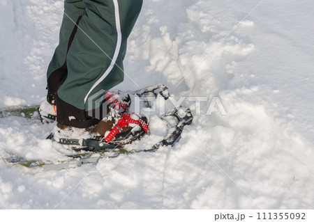 Detail, close view to snowshoes, side view, man walks in the snow. Detail, close view to snowshoes, side view, man walks in the snow. 111355092
