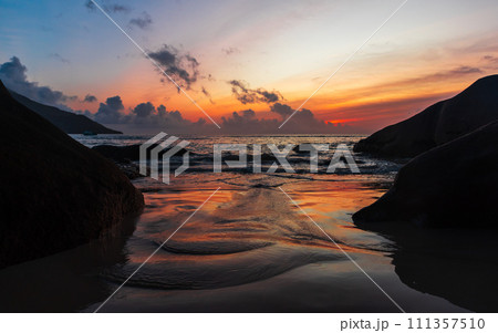 Seaside landscape photo with wet sand and coastal stones on the sunset Seaside landscape photo with wet sand and coastal stones on the sunset 111357510