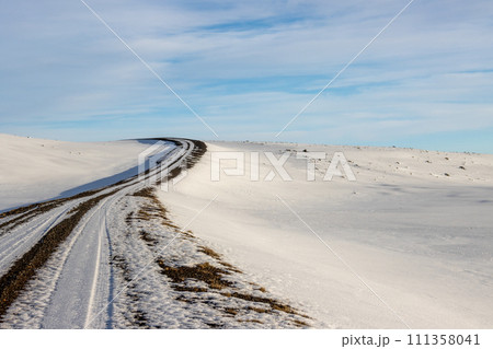 Gravel side road and a white snowy country, Iceland 111358041