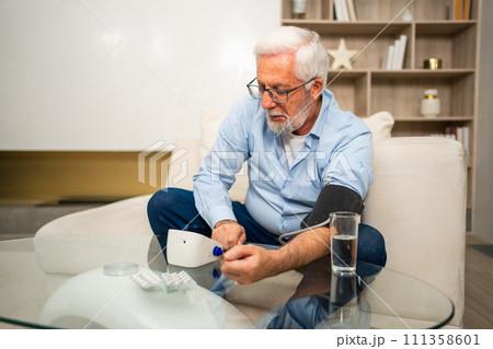 Hypertension problem in senior age. Old man measuring blood pressure with tonometer at home. Senior man have health problem making self checkup. Headache treatment of hypertension hypotension Hypertension problem in senior age. Old man measuring blood pressure with tonometer at home. Senior man have health problem making self checkup. Headache treatment of hypertension hypotension 111358601