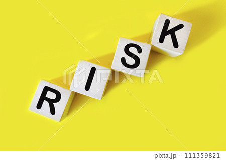 The word RISK. Wooden letter cubes isolated on a yellow background with copy space available. The word RISK. Wooden letter cubes isolated on a yellow background with copy space available. 111359821