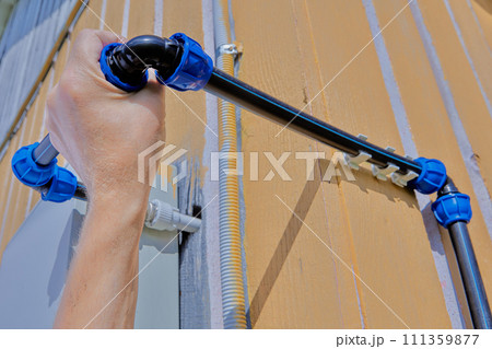 Attaching an angle pipe fitting with a compression threaded clamp to domestic outdoor water supply system for watering and irrigation, assembled from HDPE pipes. Attaching an angle pipe fitting with a compression threaded clamp to domestic outdoor water supply system for watering and irrigation, assembled from HDPE pipes. 111359877