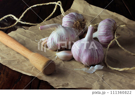Garlic bulbs on packing paper, on rustic wooden table. Closeup garlic Garlic bulbs on packing paper, on rustic wooden table. Closeup garlic 111360822
