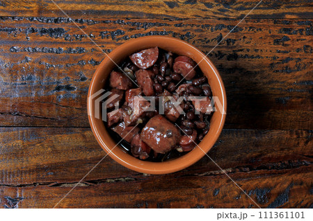 pot with feijoada, traditional brazilian cuisine dish, isolated under wooden background 111361101